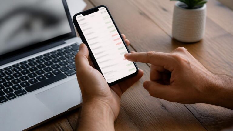 Pessoa verificando extrato bancário no celular para identificar cobranças de aplicativos