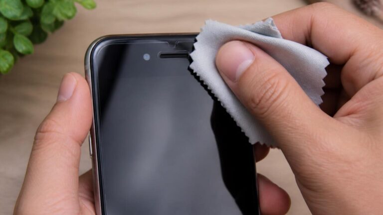 Pessoa limpando a área do sensor de proximidade de um smartphone próximo ao alto-falante