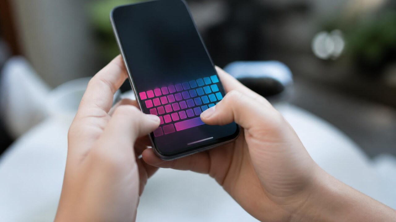 Mãos segurando um celular com teclado virtual personalizado na tela